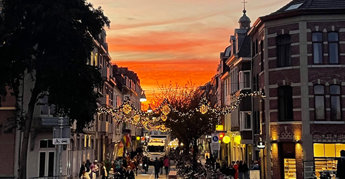 Sunset over a street lined with shops and people