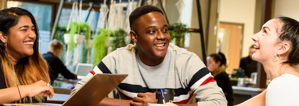 Three students sat around a table in the Law and Social Justice Building