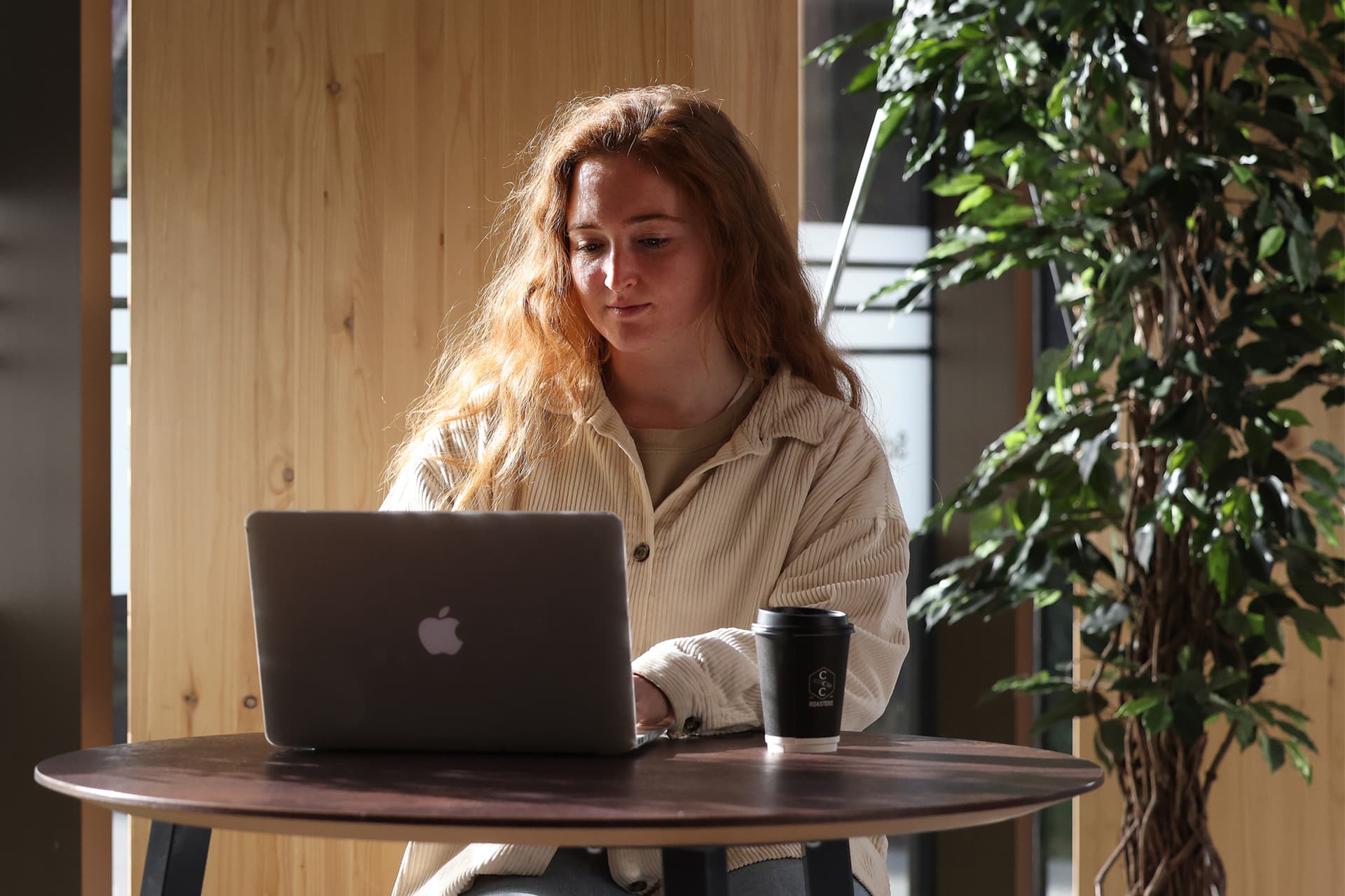 A students sits a table working on a laptop.