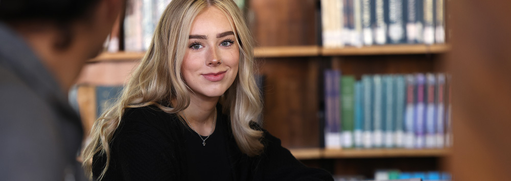 Student in the library surrounded by books