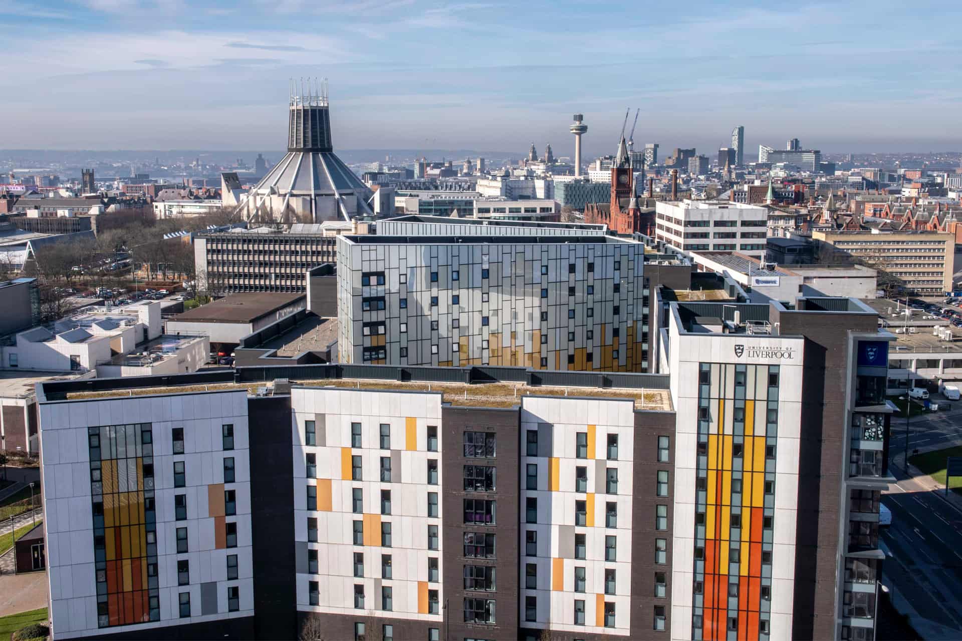 Arial view of Aerial view of a modern cityscape featuring a mix of contemporary and historic architecture. In the foreground, Aerial view of a modern cityscape featuring a mix of contemporary and historic architecture. In the foreground, there are several multi-story buildings with colorful facades, which are University of Liverpool student accommodation.