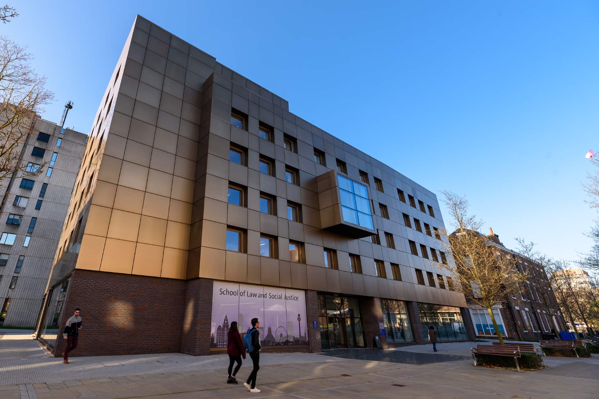 The School of Law and Social Justice, a modern multi‑storey building with bronze‑coloured panels and large windows.