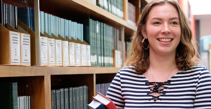 student walks through the library with books in hand