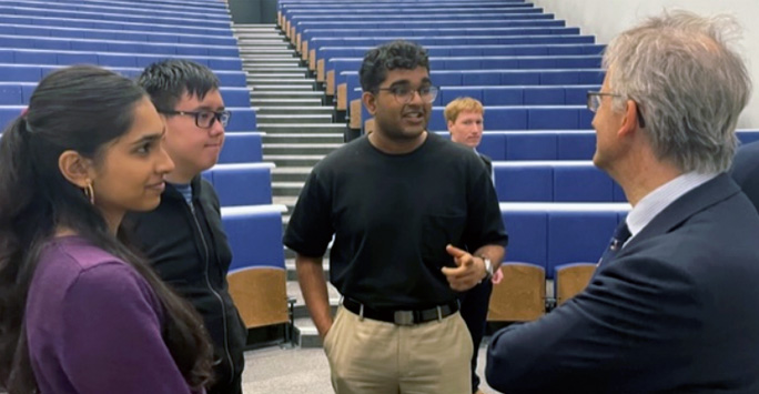Mr Justice Foxton and three students stood in a circle in conversation.