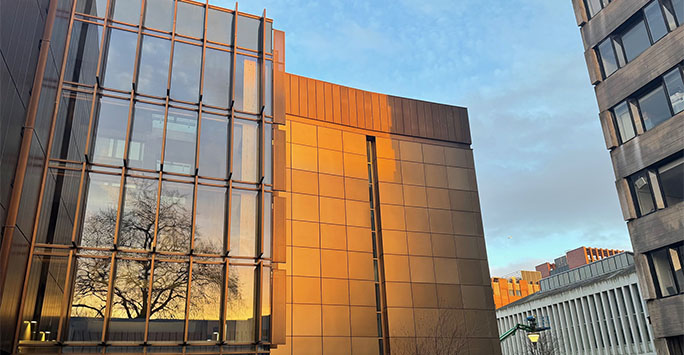 A tree reflected in the back of the School of Law and Social Justice building