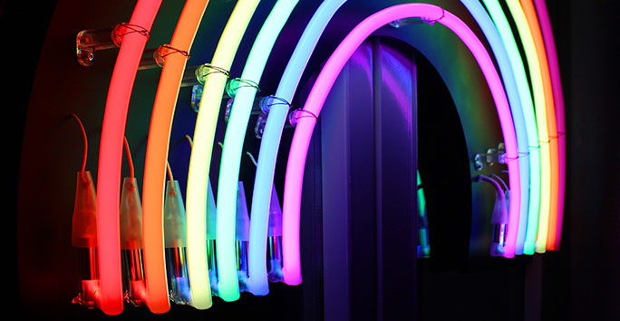 Neon tube lighting in the shape of a rainbow against a black background
