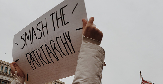 Girl at protest holding up 'Smash the Patriarchy' sign