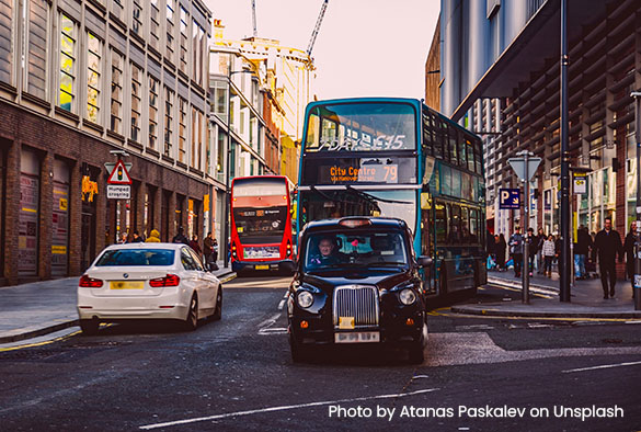 Traffic on Liverpool's Hanover street: a white mercedes, a black taxi cab and two double decker buses