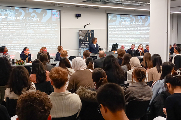 Panel discussion titled \'Pathways to the Judiciary\' at the School of Law and Social Justice, with speakers and a large audience.
