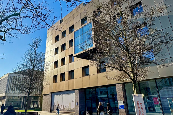 Exterior of the School of Law and Social Justice building with bronze panels and a large glass window.