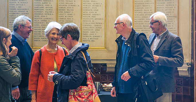 A group of Alumni smile as they greet each other.