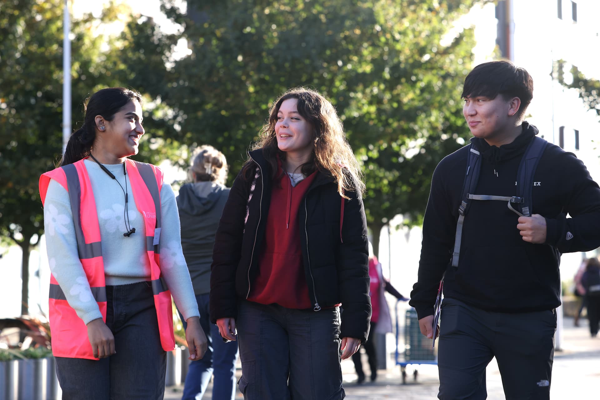 Three people walking outdoors together on a sunny day.