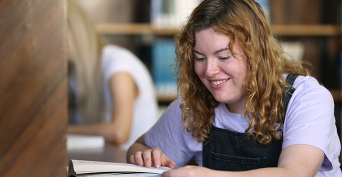 A student sat at a desk reading a book