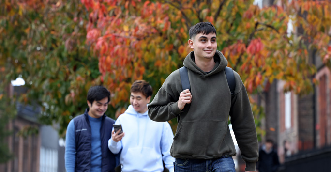 Students walk through campus surrounded by trees with orange coloured leaves