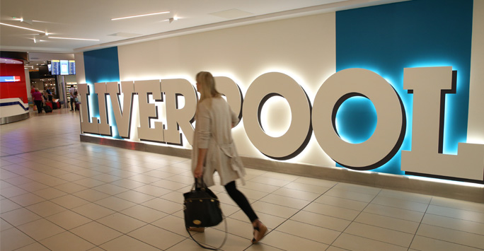 A woman carrying a bag walks past a large Liverpool sign