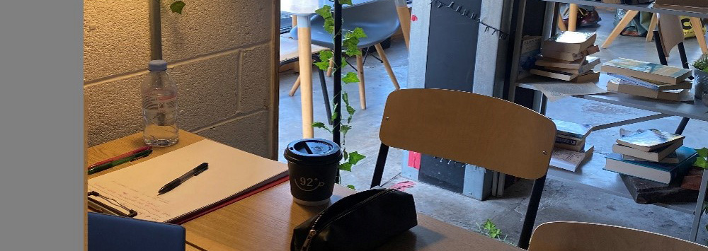 Desk in a coffee shop with laptop, stationary and coffee