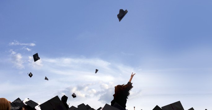 Graduate throwing mortar board into the air