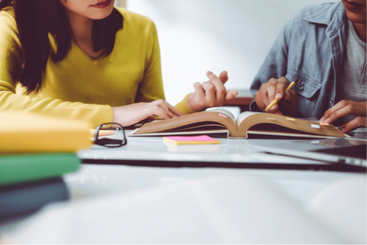 Two people studying over an open book