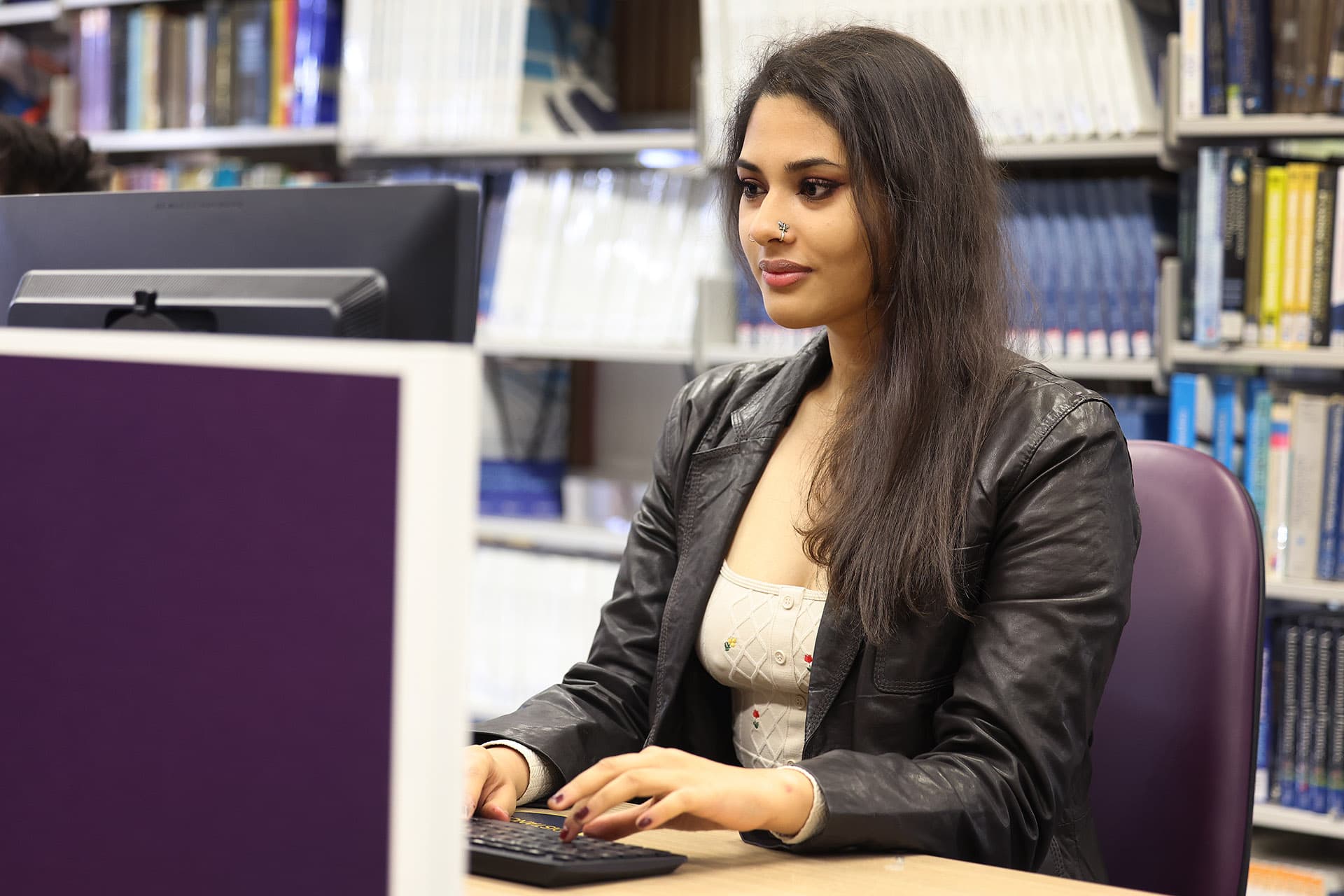 Student using a computer in the library at a desk