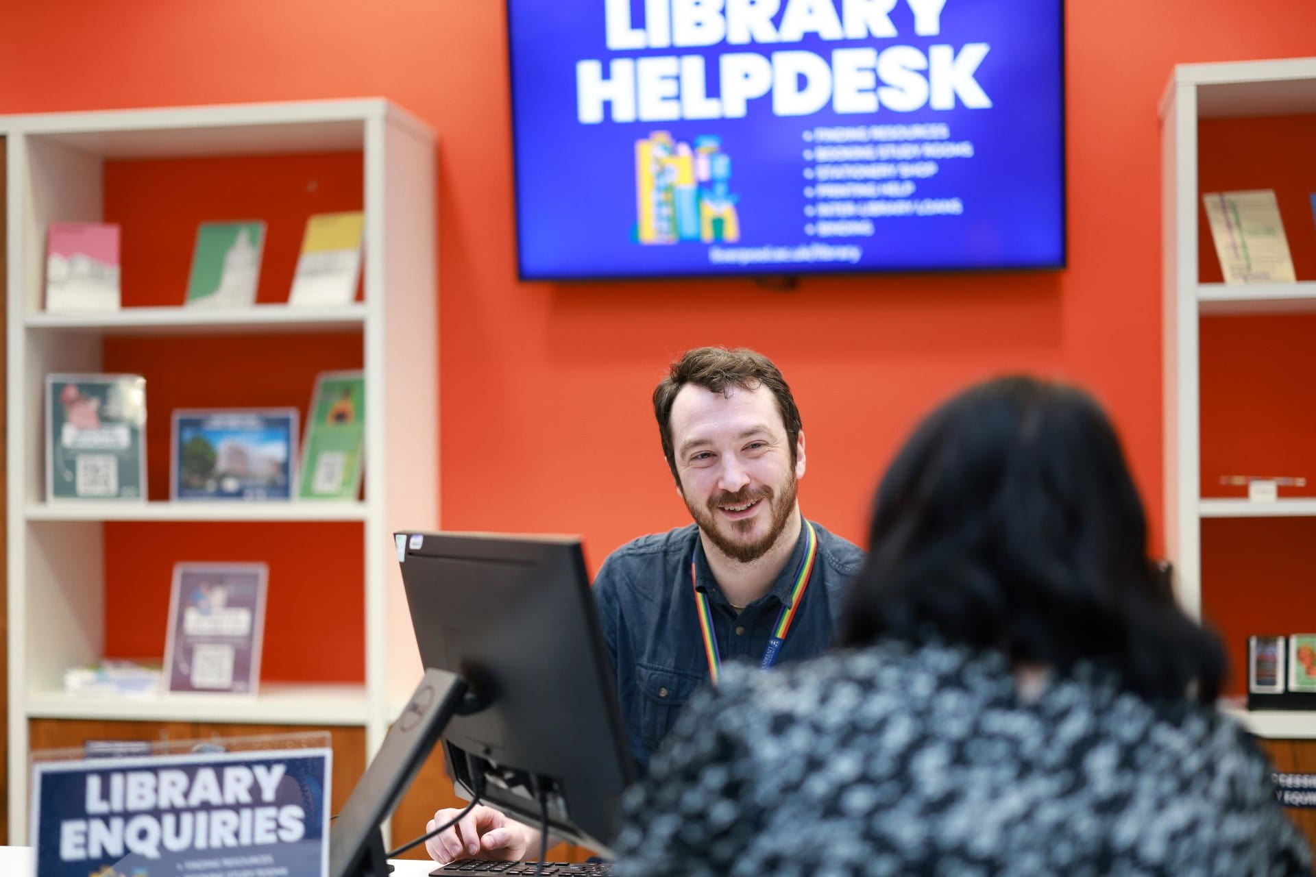 A library staff member helping a student at the helpdesk in the Sydney Jones Library