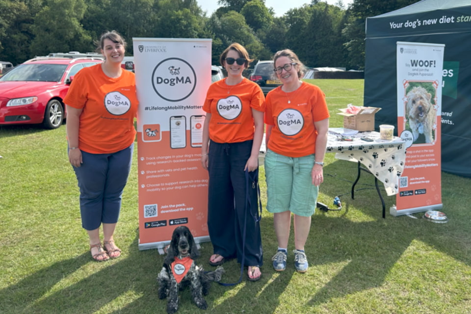 A photo of three researchers at their stand at DogFest, complete with well behaved dog