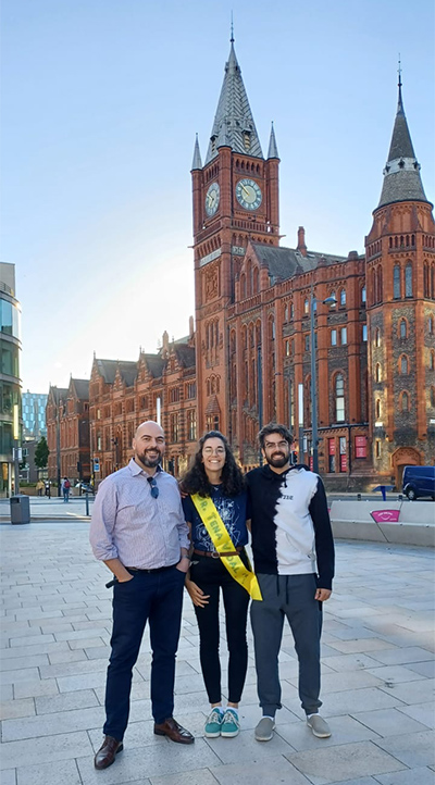 Three people standing in front of the Victoria Building