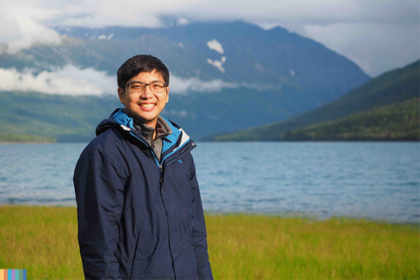 person posing for a picture in front of a lake