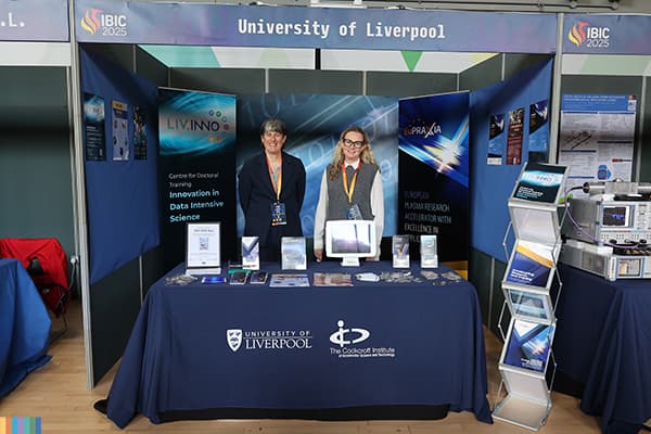 Two people posing for a picture at an industry stand.