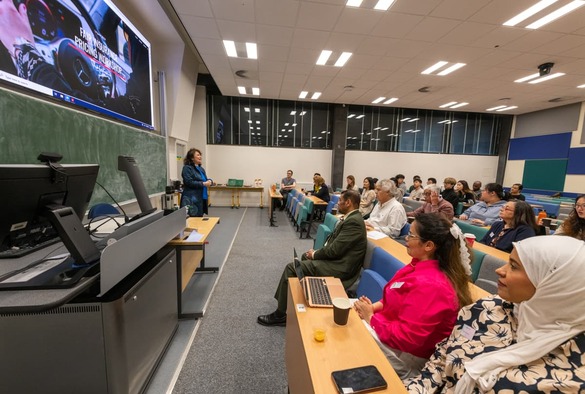 A woman presenting to a large audience, engaging them with her speech and visual aids.