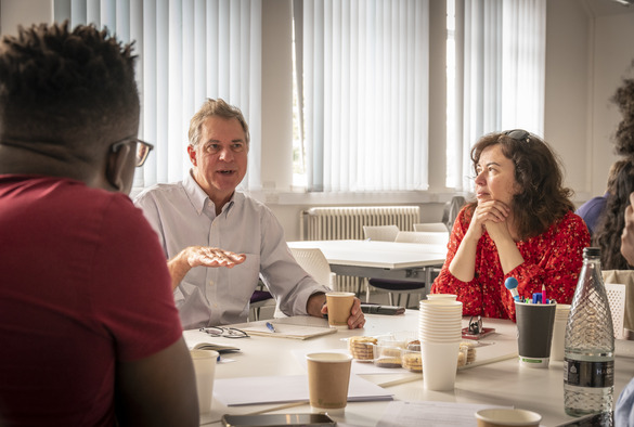 A diverse group of people engaged in conversation around a table, sharing ideas and discussing various topics.