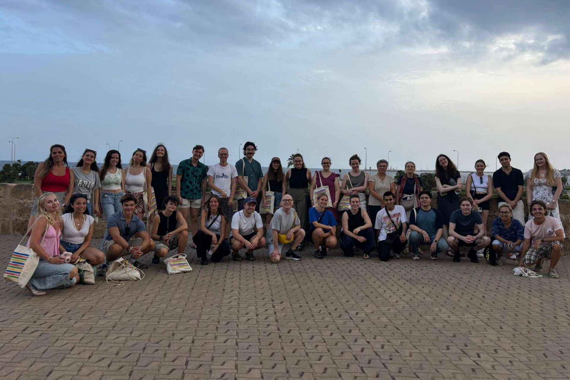 A large group of students standing together outside by a coastline.