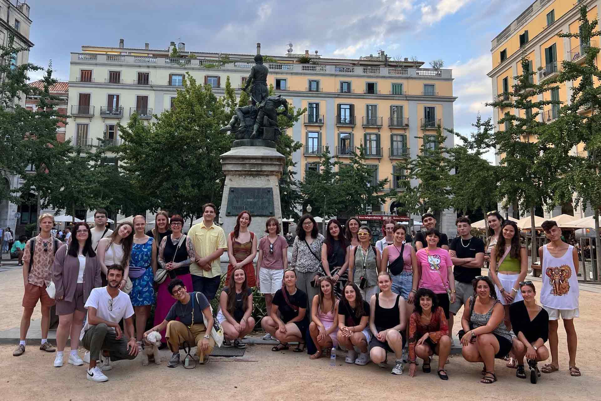 A group of young people standing in the centre of a European town square.