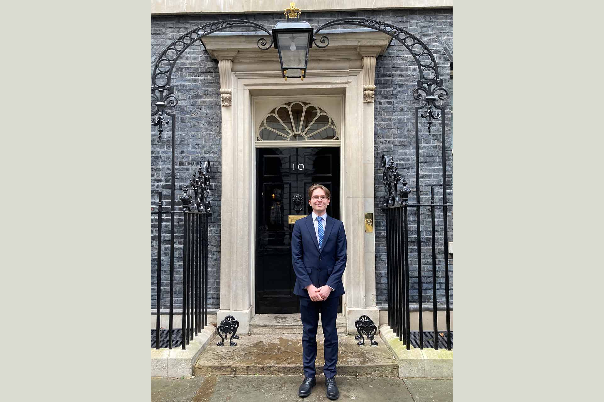 A young man standing in front of the door of 10, Downing Street.