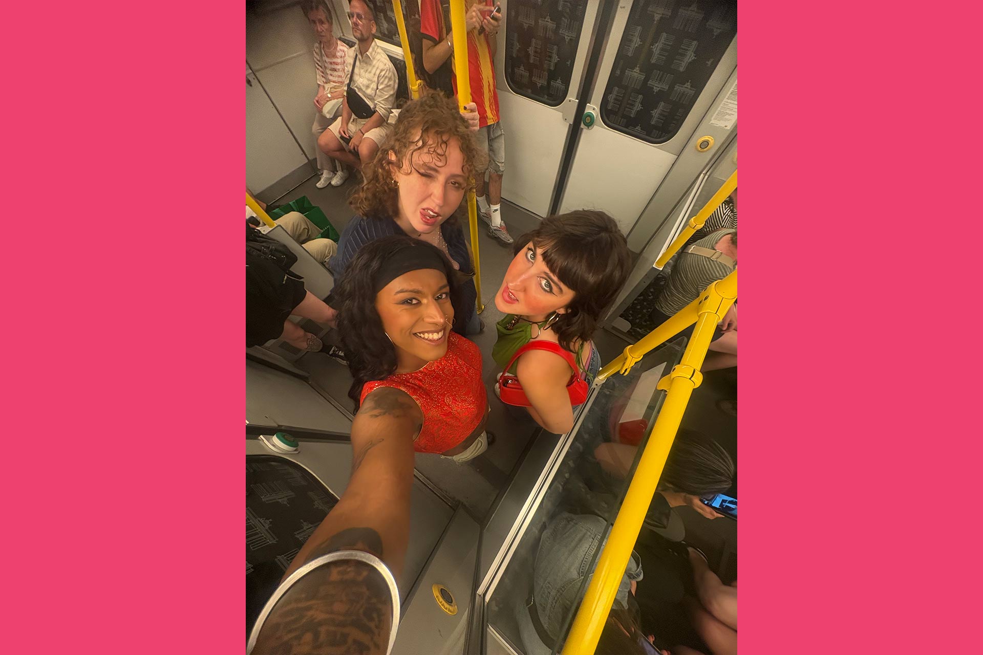 3 students on public transport standing together taking a selfie at arms length above their heads.
