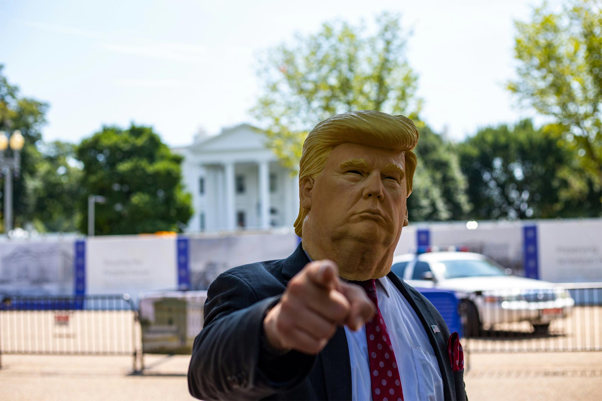 A person wearing an oversized mask/head of Donald Trump