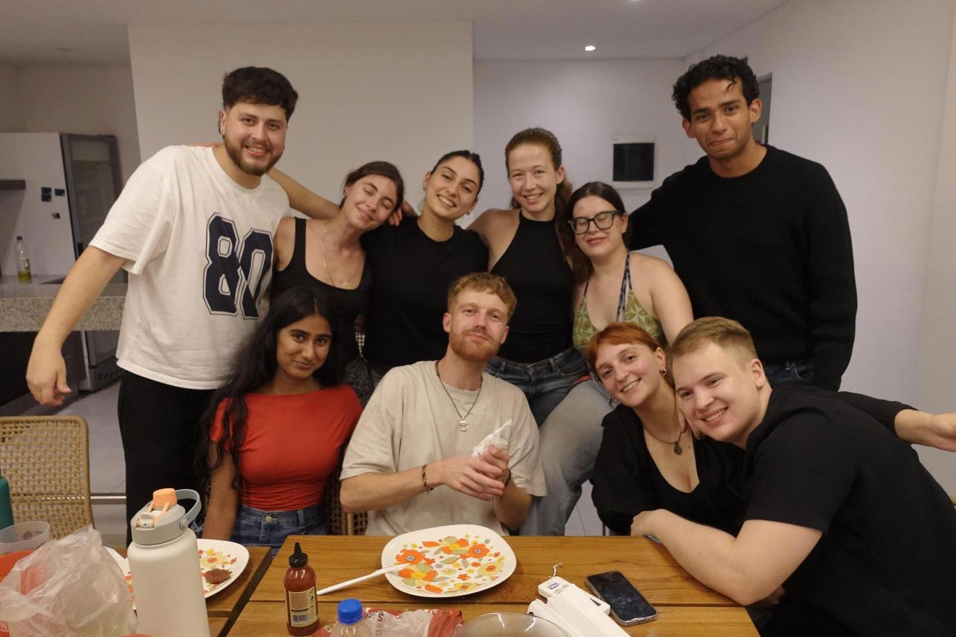 A group of young people gathered around a table smiling
