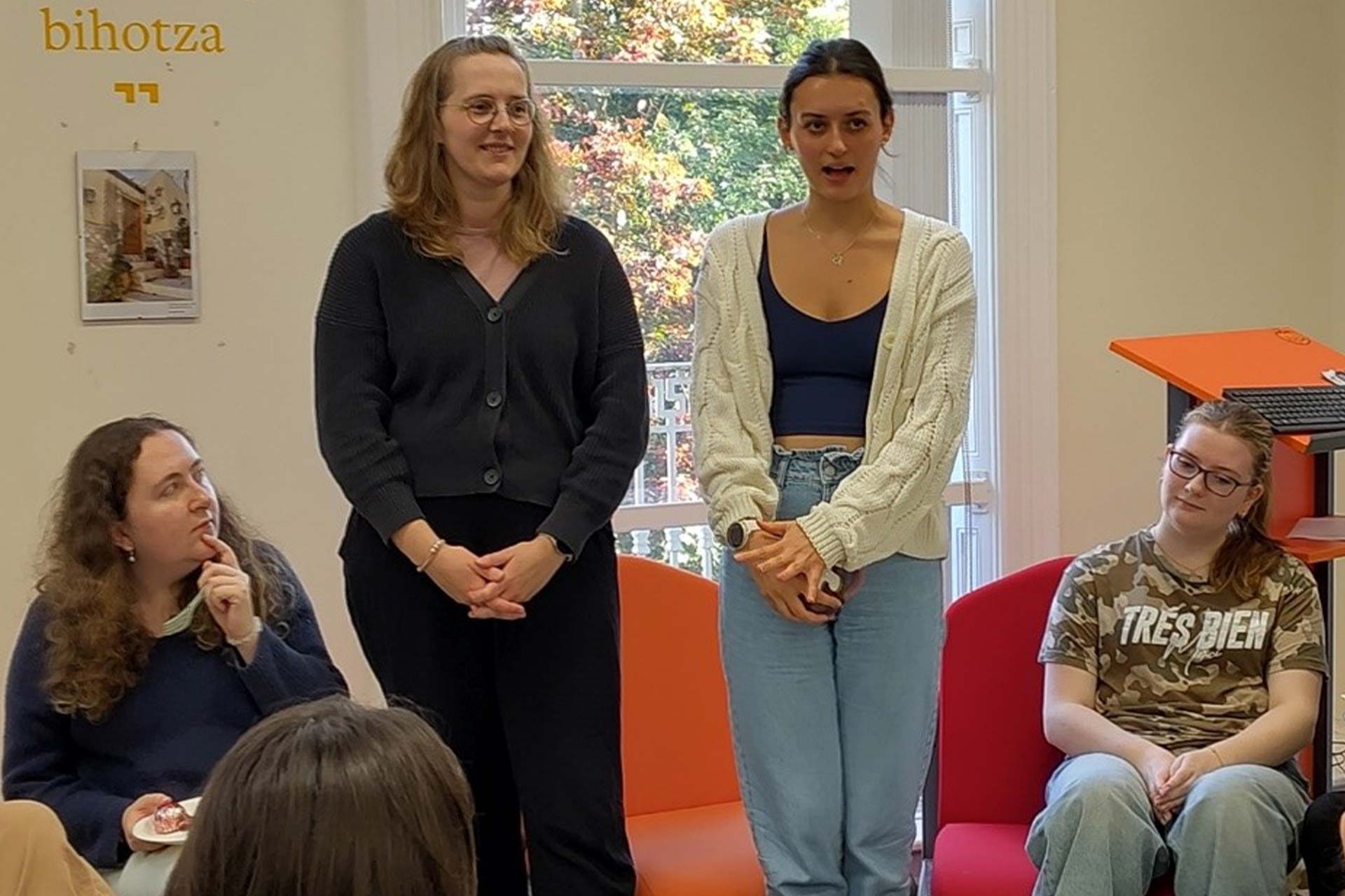 Two women standing and talking to a group of students sitting down in the Language Lounge.