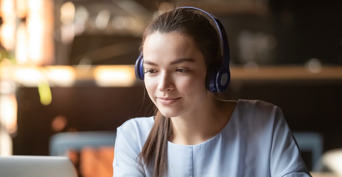 Student with headphones looking at language resources on a laptop