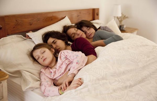 Family of four sleeping in a bed