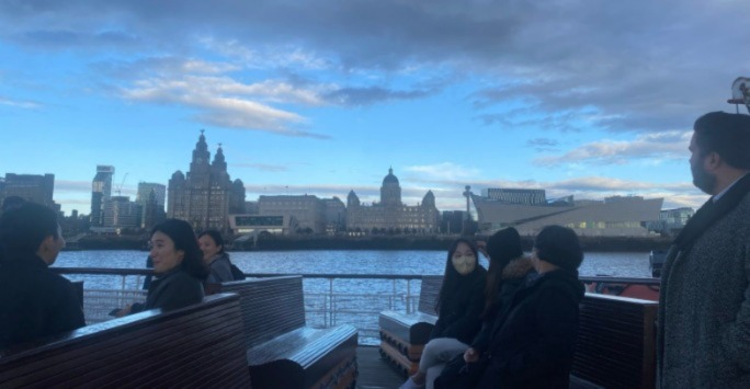 Sogang University and National Musuem Liverpool network members on the Mersey Ferry, Liverpool with the Three Graces and the Museum of Liverpool in the background