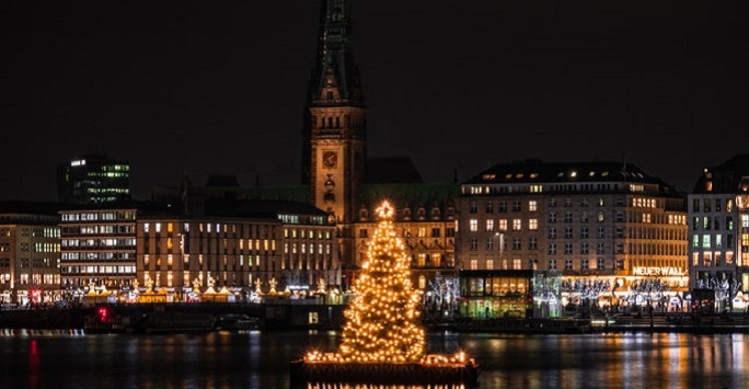 Hamburg city skyline at night during Christmas, with a lit up christmas tree in the foreground