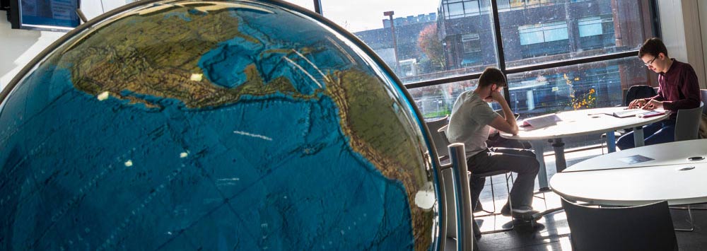 Two students studying and a globe