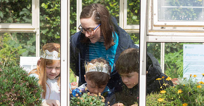 Three children study plants in a greenhouse at Ness Botanic Gardens.