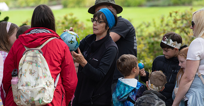 A group of children and staff on a school visit to Ness Botanic Gardens, with one member of staff holding a globe.