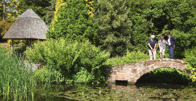 visitors standing on the stone bridge by the summer house in Ness Gardens