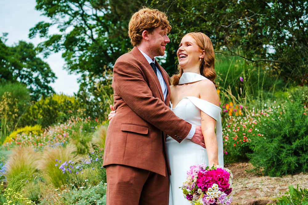 A couple embrace as they walk through the gardens after their wedding ceremony.