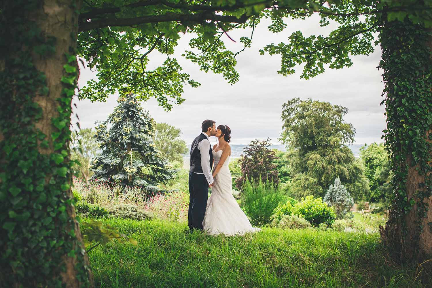 A couple kiss, surrounded by the stunning greenery of Ness, as they celebrate their wedding.