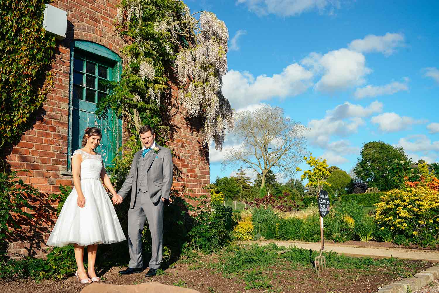 A couple pose for a photo outside a building as they explore the grounds of Ness after their wedding ceremony.