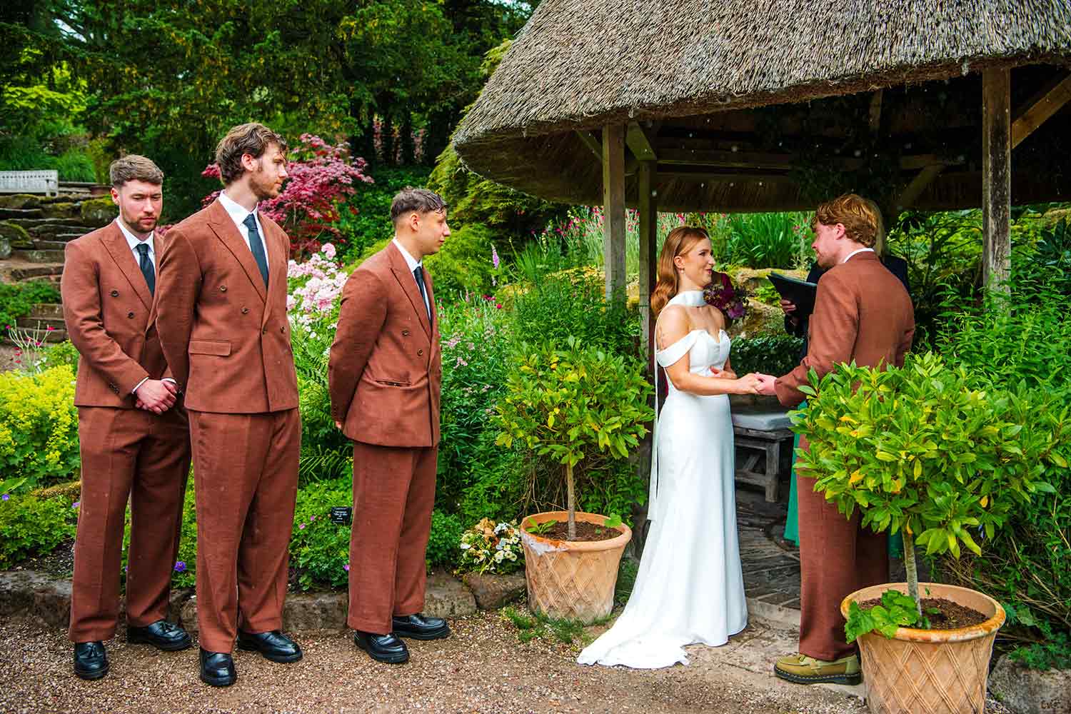 A wedding ceremony takes place under the thatched gazebo in the Rock Garden.
