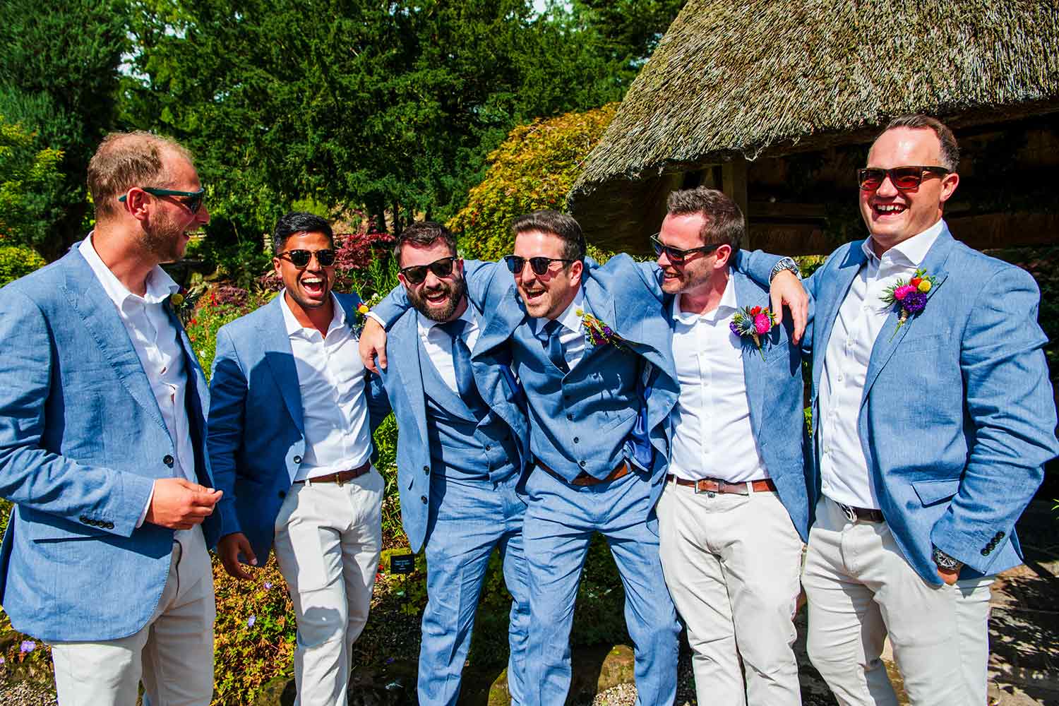 A group of wedding guests chat near the thatched gazebo in the Rock Garden.